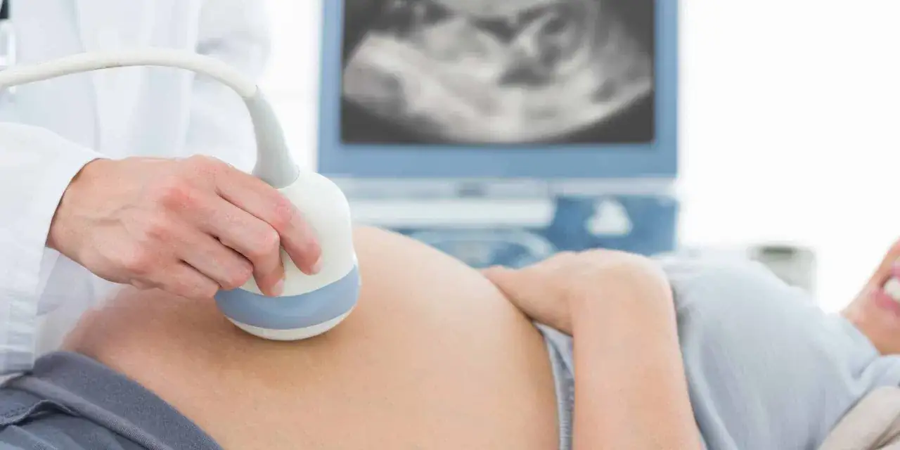 Ecografia di un feto di 21 settimane, con un medico che usa una sonda su una pancia incinta.