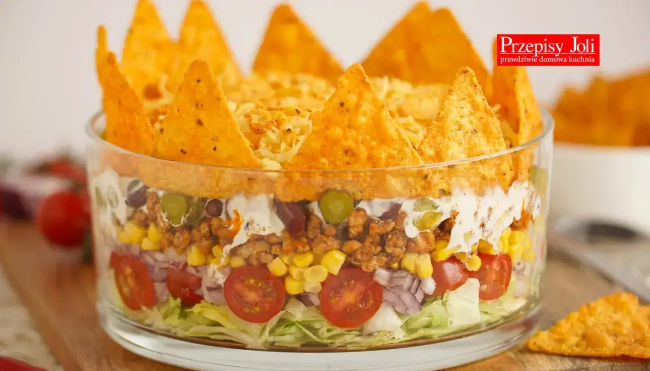 Warstwowa sałatka z nachos, mięsem mielonym, kukurydzą i warzywami. Idealna na imprezę, jedna z 10 najlepszych sałatek na imprezę.