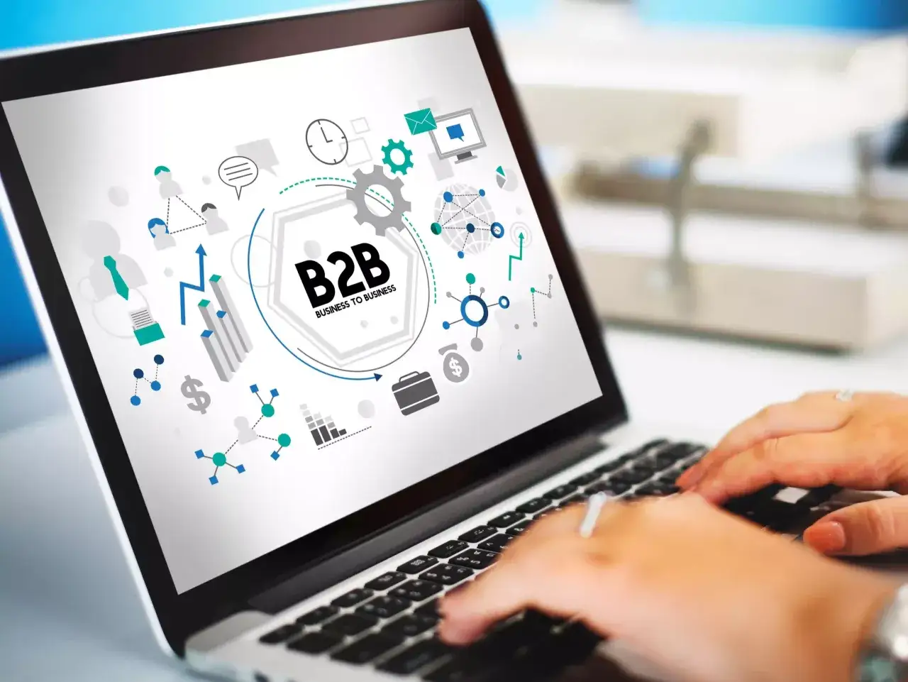 Grafika na ekranie laptopa wyjaśnia, co to B2B (Business to Business) – relacje między firmami, z ikonami symbolizującymi współpracę, analizę i komunikację.