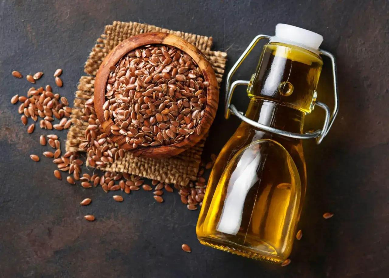 Naturalny olej lniany w butelce i nasiona lnu w drewnianej misce. Idealny do pielęgnacji twarzy.