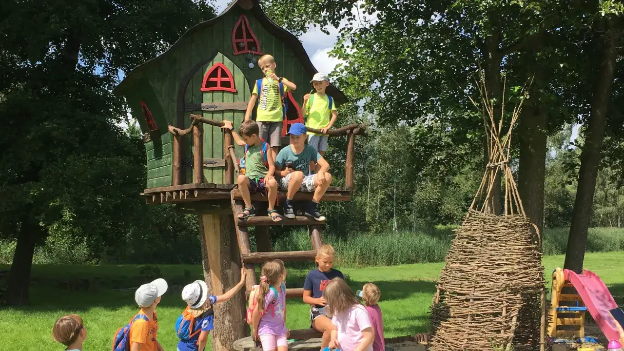 Dzieci bawią się w domku na drzewie, odkrywając **Tarnowskie Góry atrakcje**. Obok tipi i zjeżdżalnia.