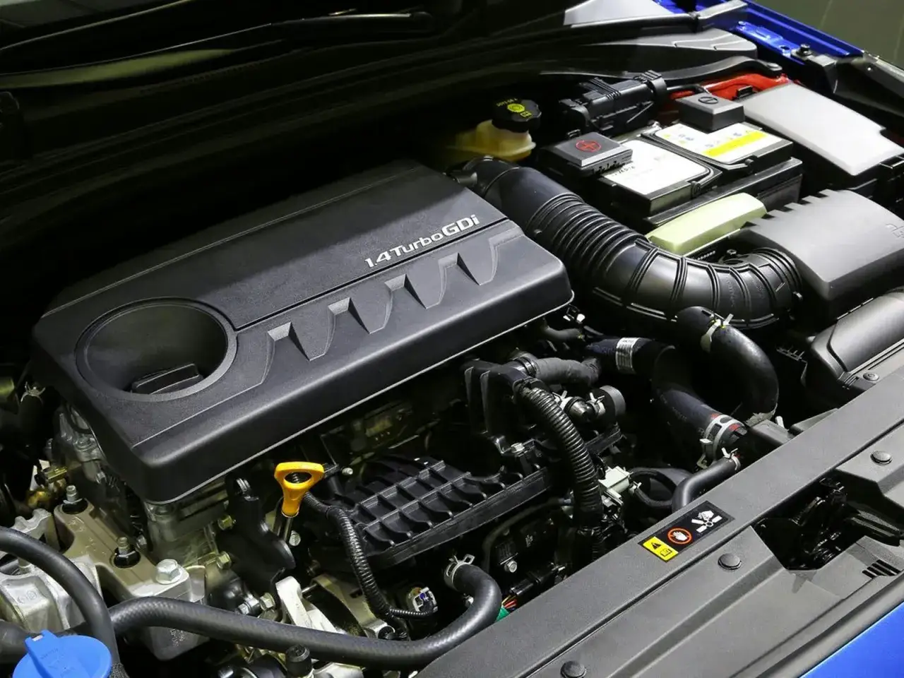 Detalle de los motores Kia 1.4 Turbo GDi, con componentes visibles como la batería y el sistema de admisión de aire.