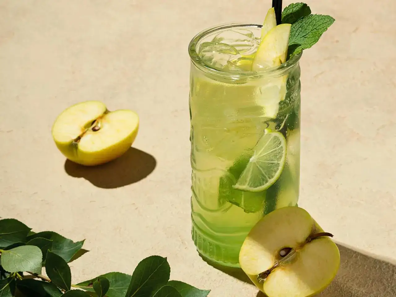 En uppfriskande p2 drink med &auml;pple, lime och mynta. Tv&aring; halvor av ett gr&ouml;nt &auml;pple ligger bredvid glaset.