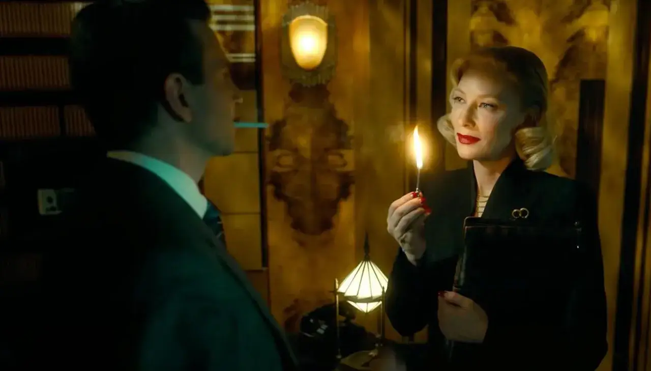 A woman with blonde hair and red lipstick lights a match, her gaze intense. The scene evokes the dramatic lighting style of Alex Majoli.