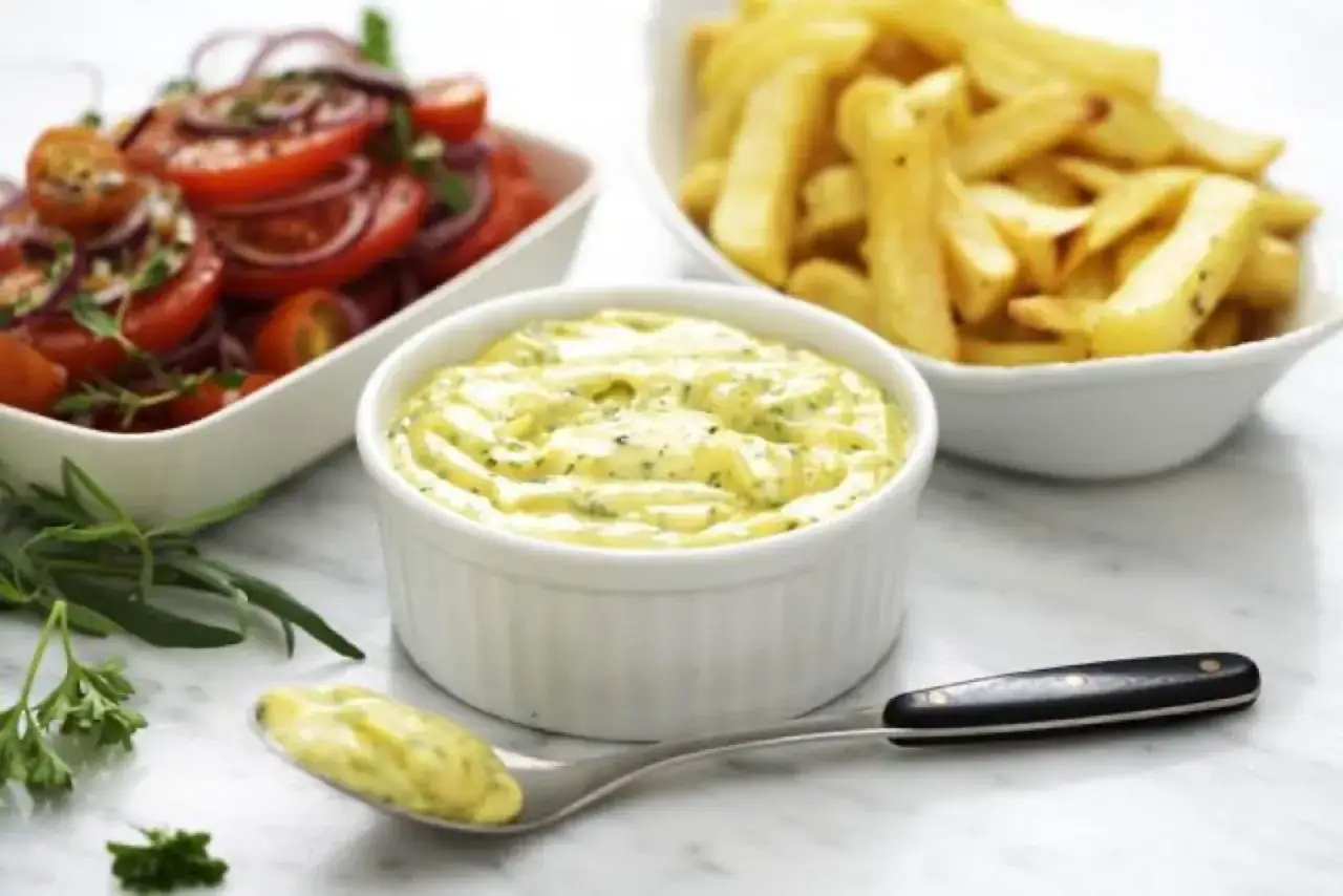 En sk&aring;l med kr&auml;mig bearnaises&aring;s, perfekt f&ouml;r ditt bearnaises&aring;s recept. Bredvid syns en tomat- och l&ouml;ksallad samt pommes frites.