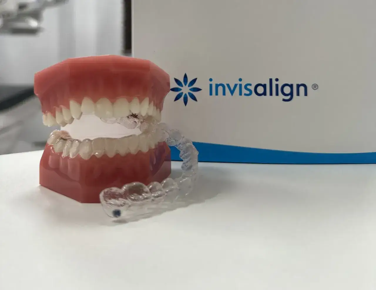 Ortodonta pokazuje, co robi, używając modelu szczęki i przezroczystych nakładek Invisalign do korekty zgryzu.