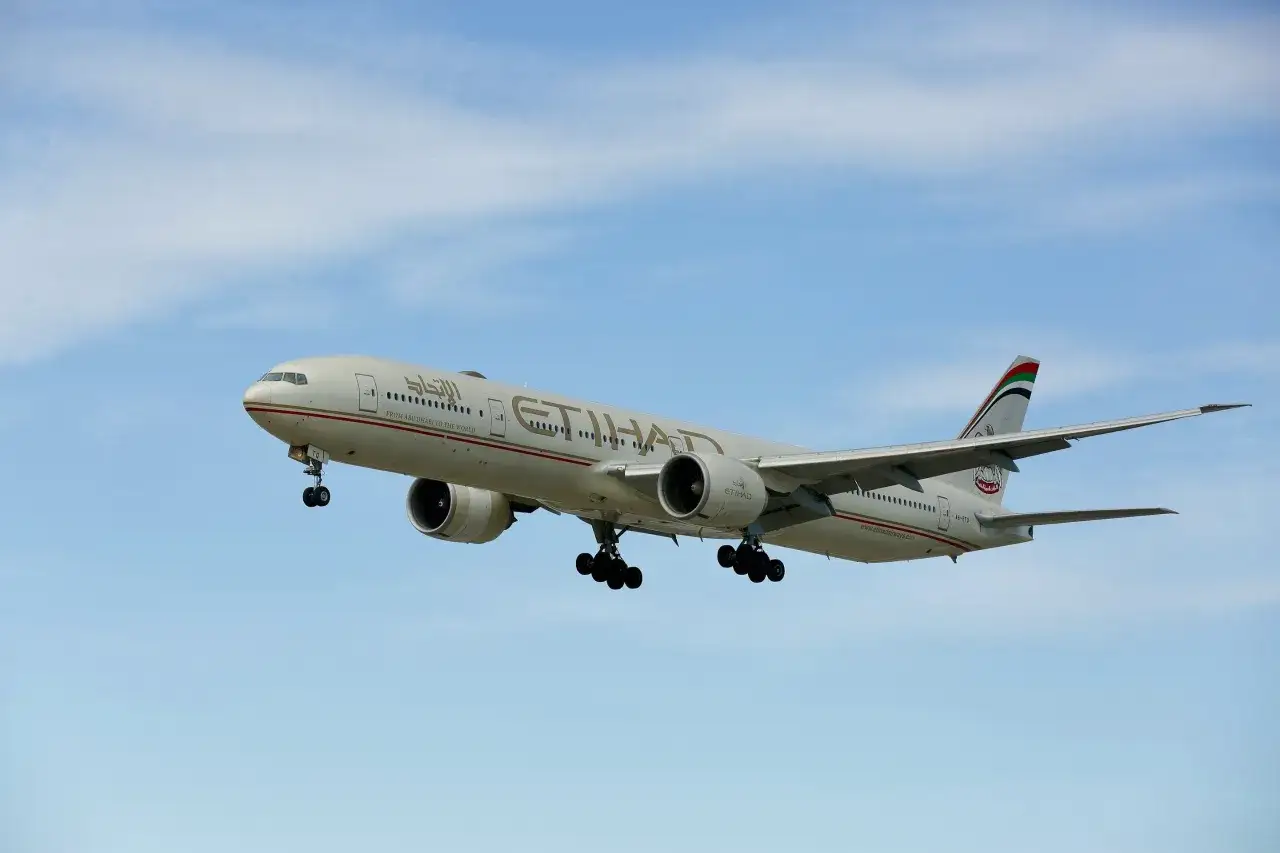 Samolot Etihad Airways z wysuniętym podwoziem, gotowy do lądowania. Zastanawiasz się, ile trwa lot do Dubaju?