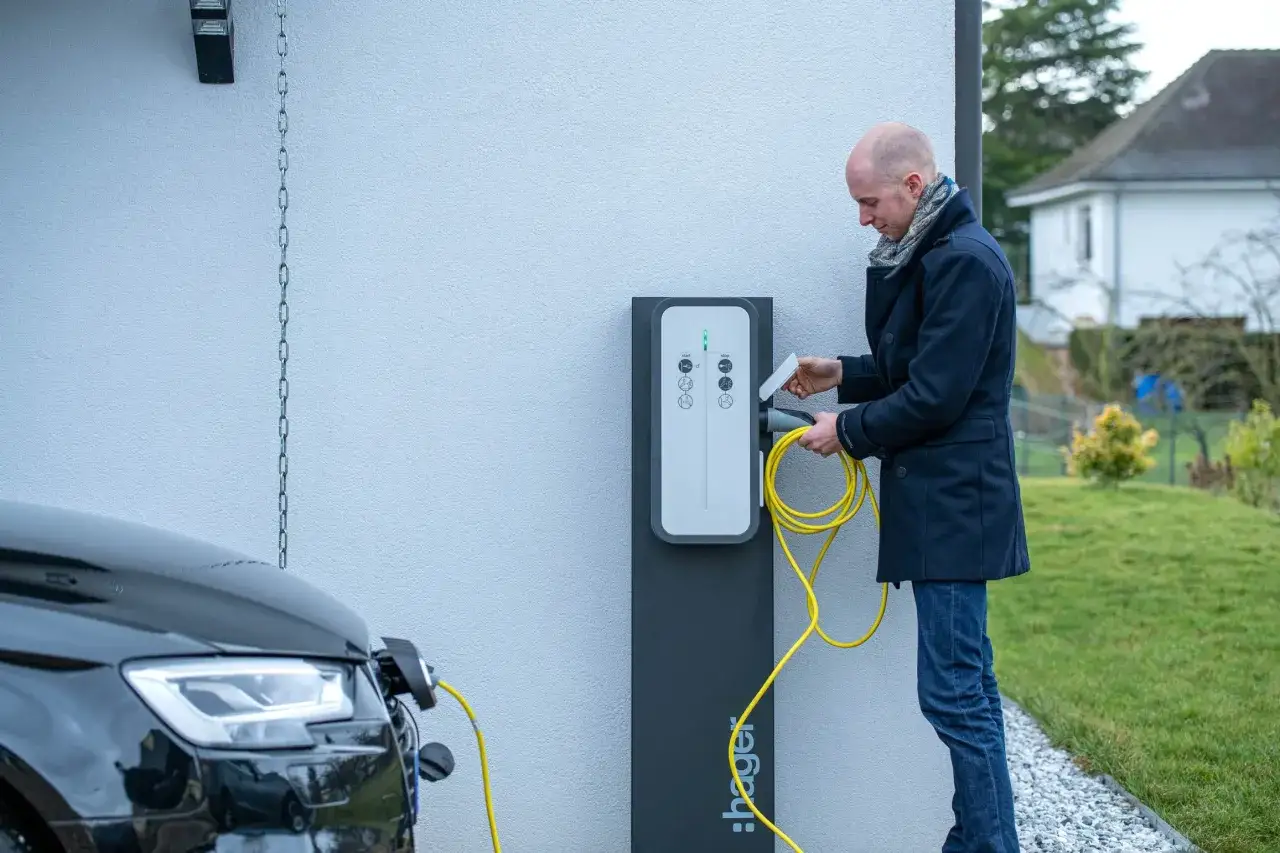 Un homme charge sa voiture &eacute;lectrique. La borne Hager est pr&ecirc;te, mais peut on installer soi meme une borne de recharge ?