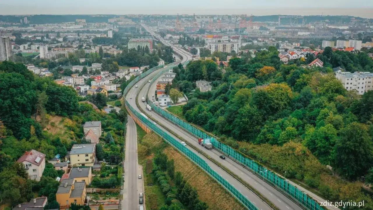 Widok na estakadę Kwiatkowskiego w Gdyni, otoczoną zielenią i zabudowaniami.