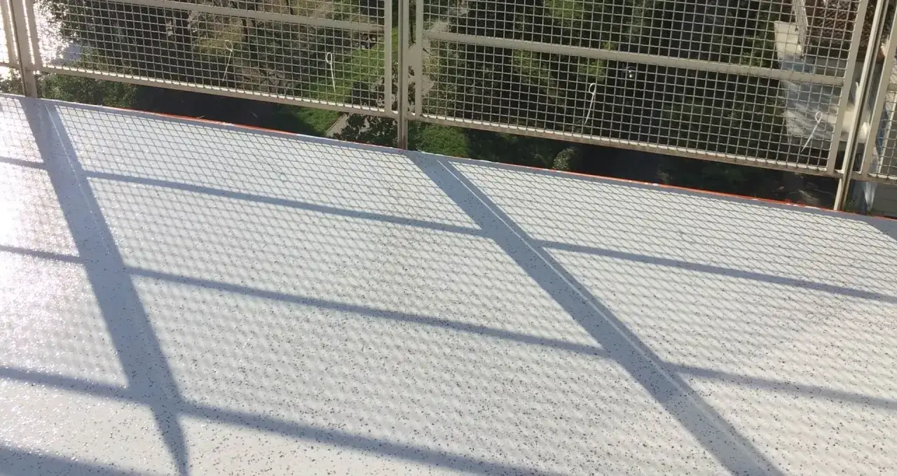 Nowe balkony z żywicy, lśniące w słońcu. Siatka balustrady rzuca cień na białą, antypoślizgową powierzchnię.