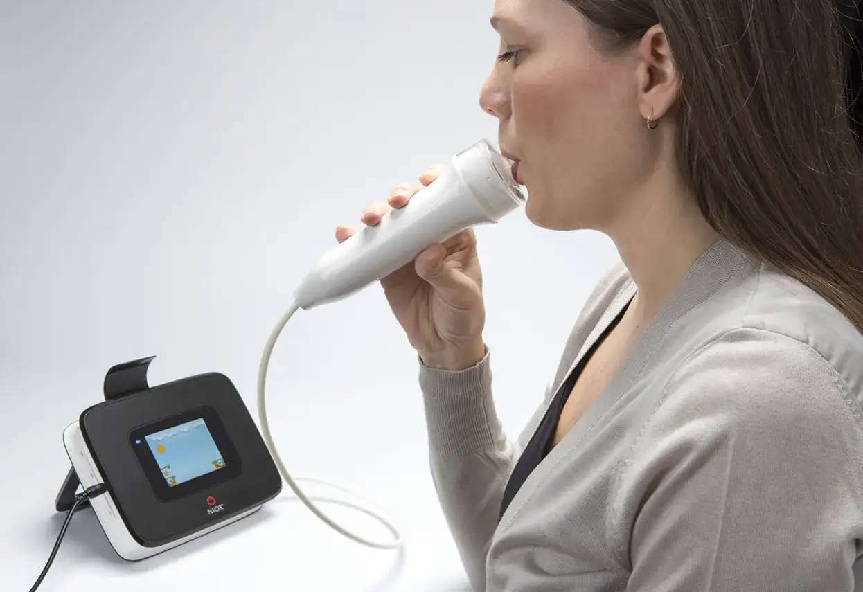 Frau nutzt ein Ger&auml;t zur Messung von Entz&uuml;ndungen der Atemwege, wichtig bei eosinophilem Asthma.
