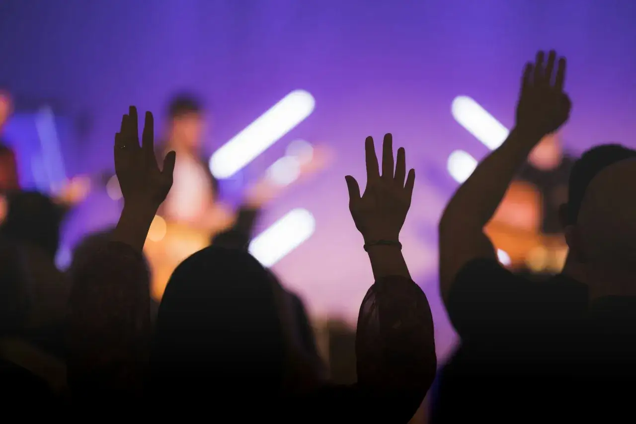 Hands raised in worship under purple lights. A moment of collective praise, a testament that god is good.