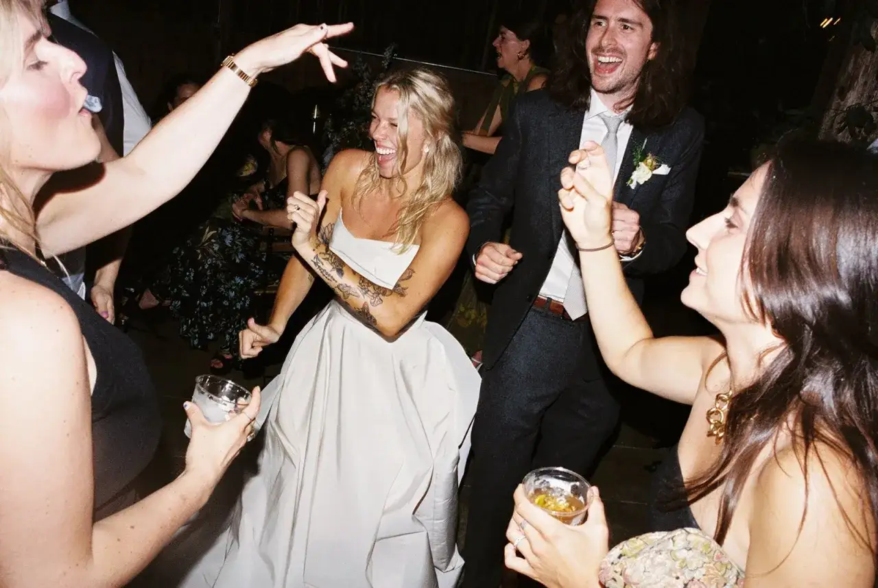 La mariée, en robe blanche, danse joyeusement avec ses invités. La musique bat son plein, l'ambiance est festive, bien avant le gâteau de mariage.