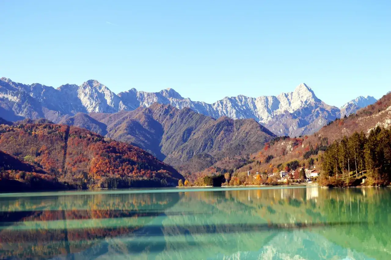 Splendido lago alpino con montagne colorate dall'autunno, ideale per camminate FVG. Riflessi perfetti sull'acqua cristallina.