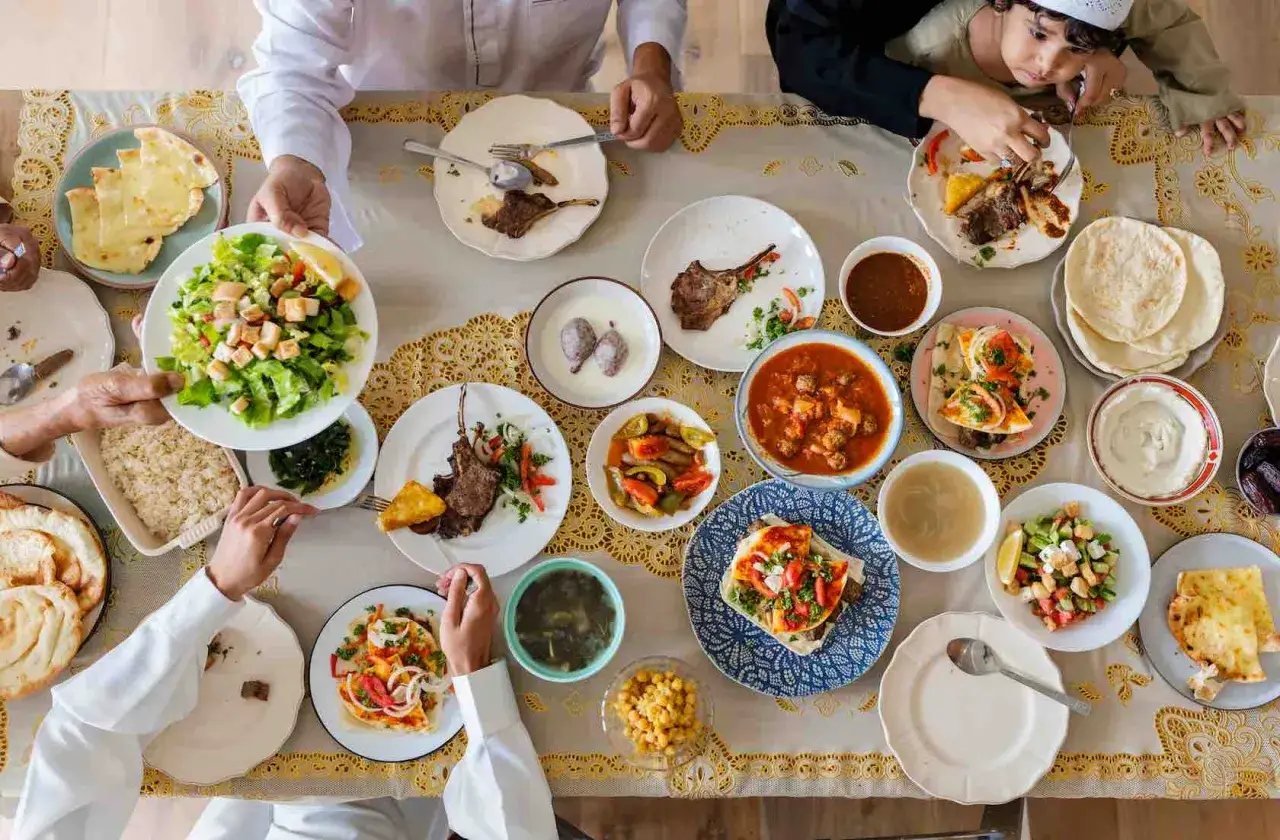 Familie genie&szlig;t ein Festmahl mit Lammkoteletts, Salat und Brot, das an die Fastenzeit im Islam erinnert.