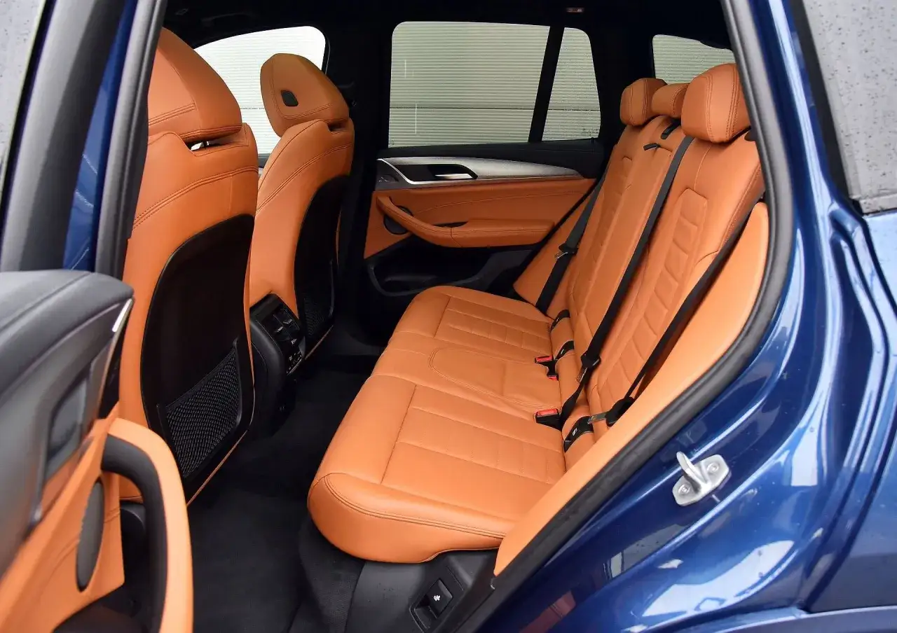 Wnętrze BMW G01 z brązową skórzaną tapicerką.
