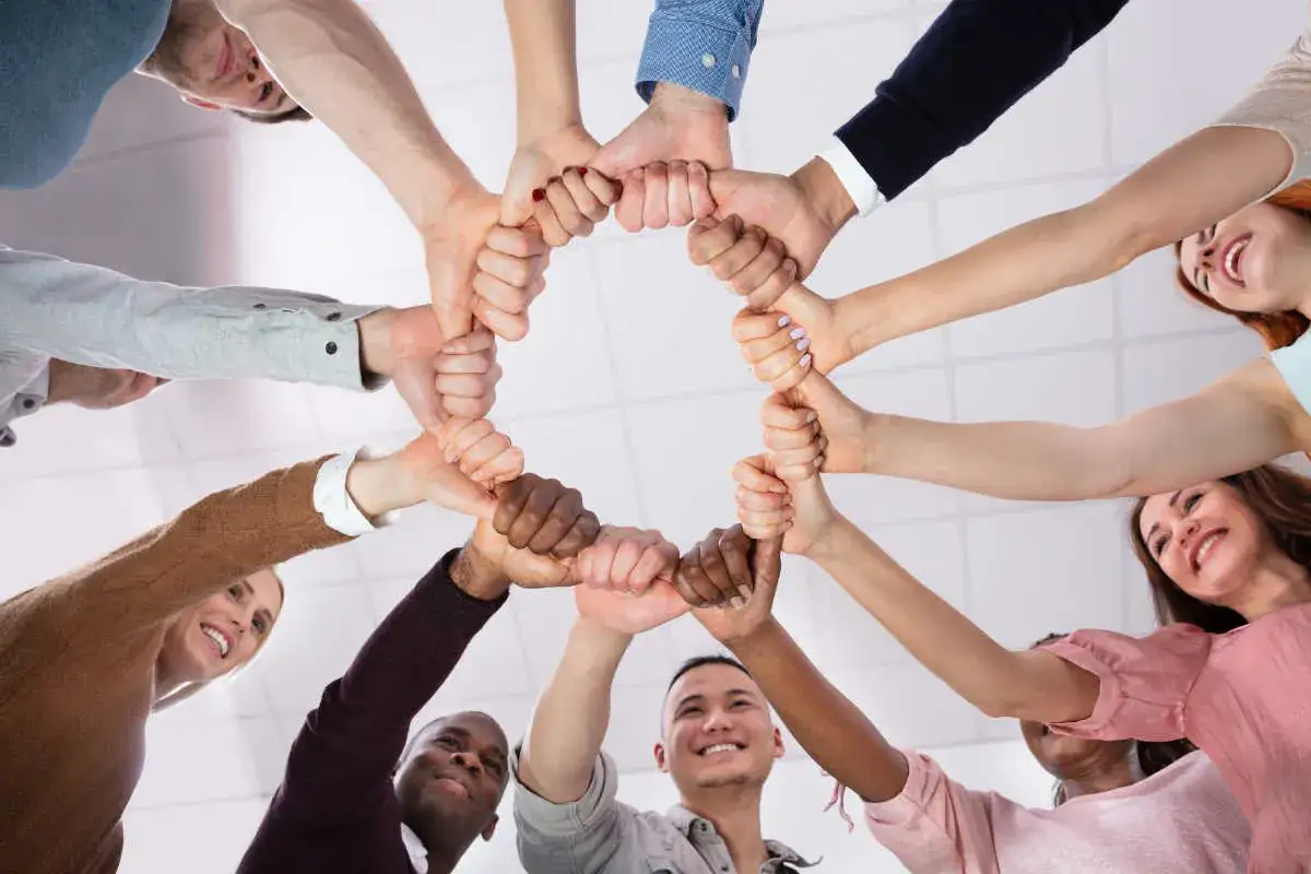 Des mains s'unissent en cercle, symbolisant la force collective. Parfaites team building idées simples pour renforcer les liens.