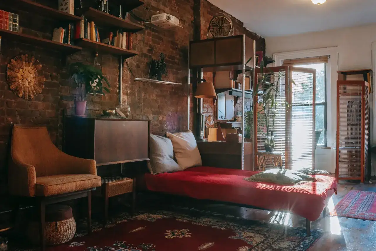 Przytulny dom w stylu vintage z ceglanymi ścianami, regałami pełnymi książek, wygodną kanapą i fotelem.