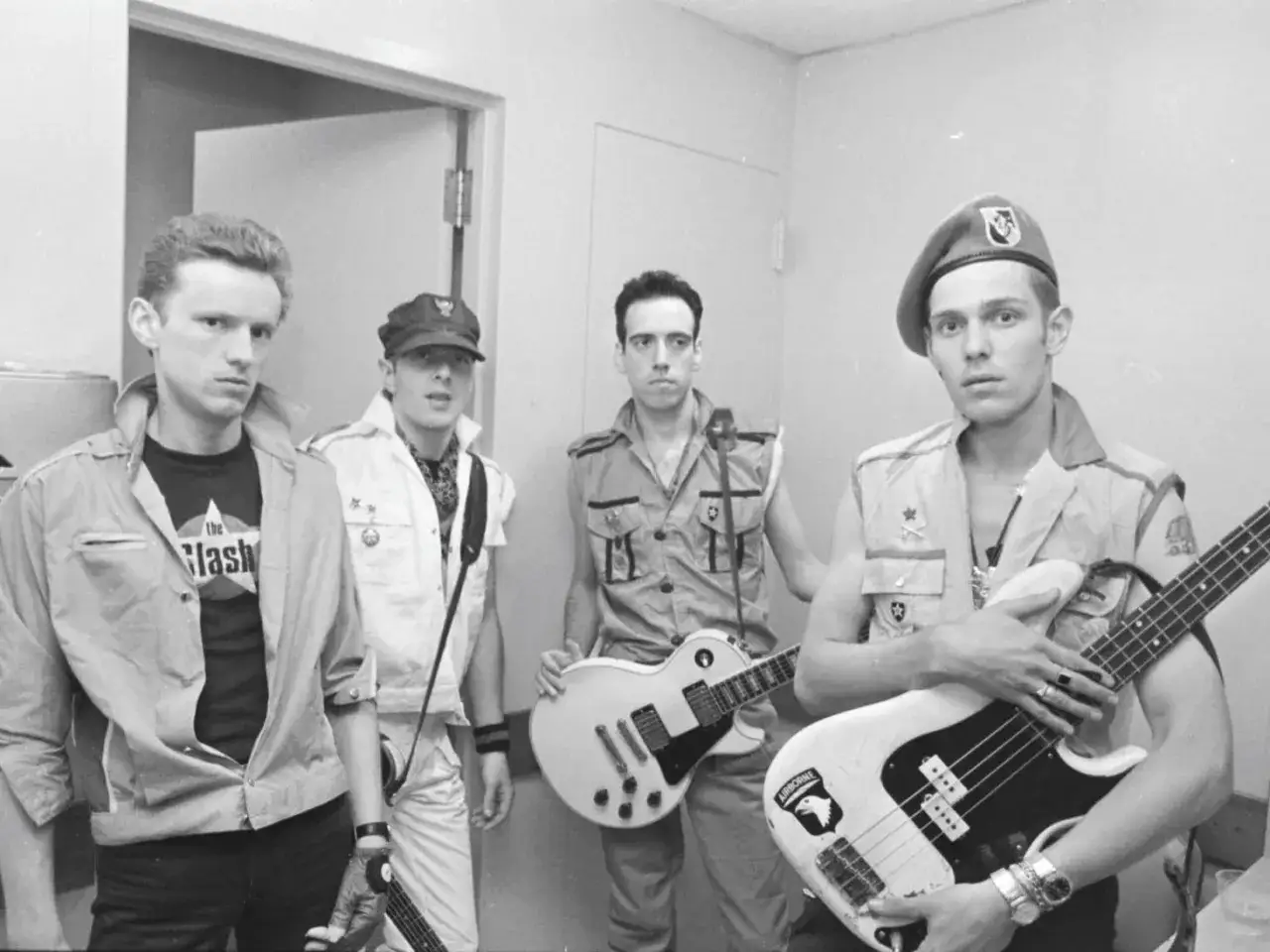 Les membres de The Clash posent avec leurs guitares. L'un porte un t-shirt 