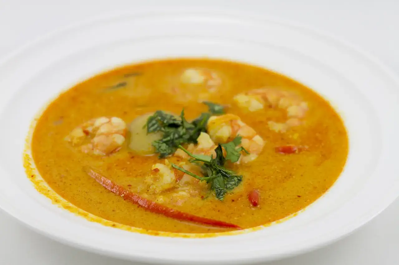Aksamitny, pomarańczowy bulion z krewetkami i ziołami. Aromatyczny tom yam, gotowy do spożycia.