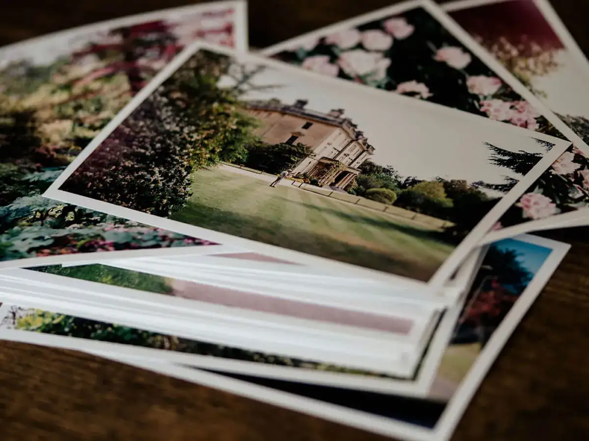 Pile di stampe fotografiche su diverse tipologie di carta per stampa: un palazzo, fiori e paesaggi.