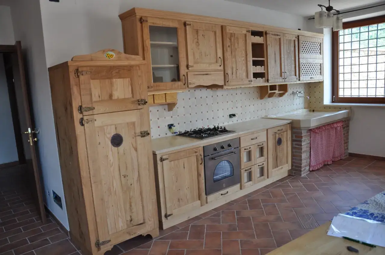 Cucina in legno grezzo con un grande armadio, piano cottura e forno. Perfetta per chi cerca idee cucina rustica.