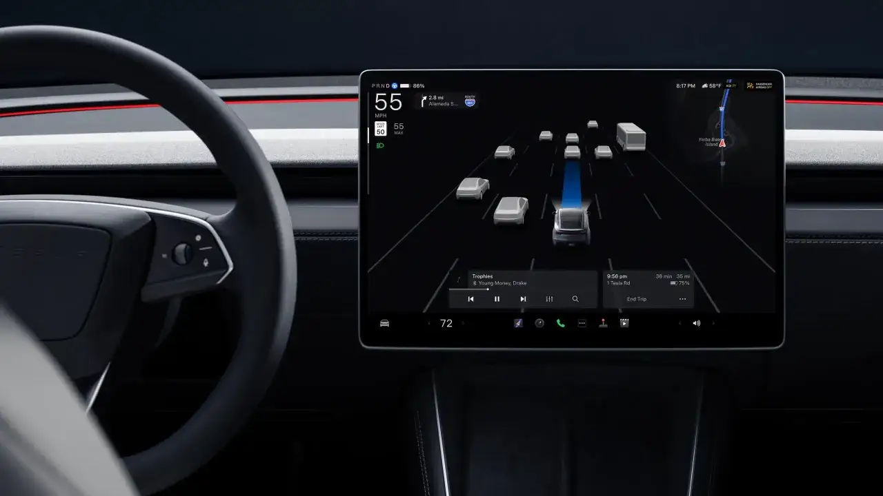 Wnętrze Tesli z ekranem pokazującym widok z kamery i nawigację. Tesla to firma znana z innowacyjnych samochodów elektrycznych.