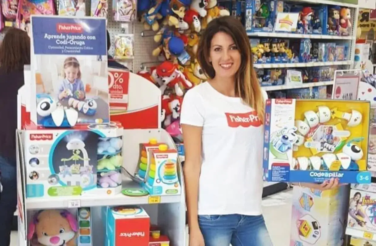 Mujer sonr&iacute;e en tienda de juguetes, mostrando el juguete 