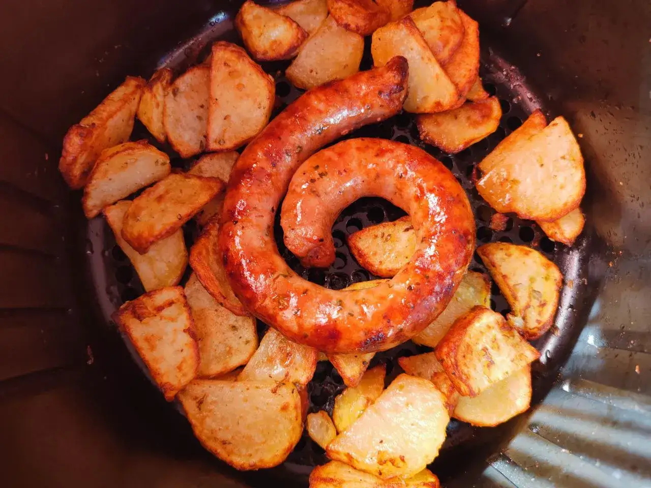 Salsiccia arrotolata e patate croccanti cotte nella friggitrice ad aria.
