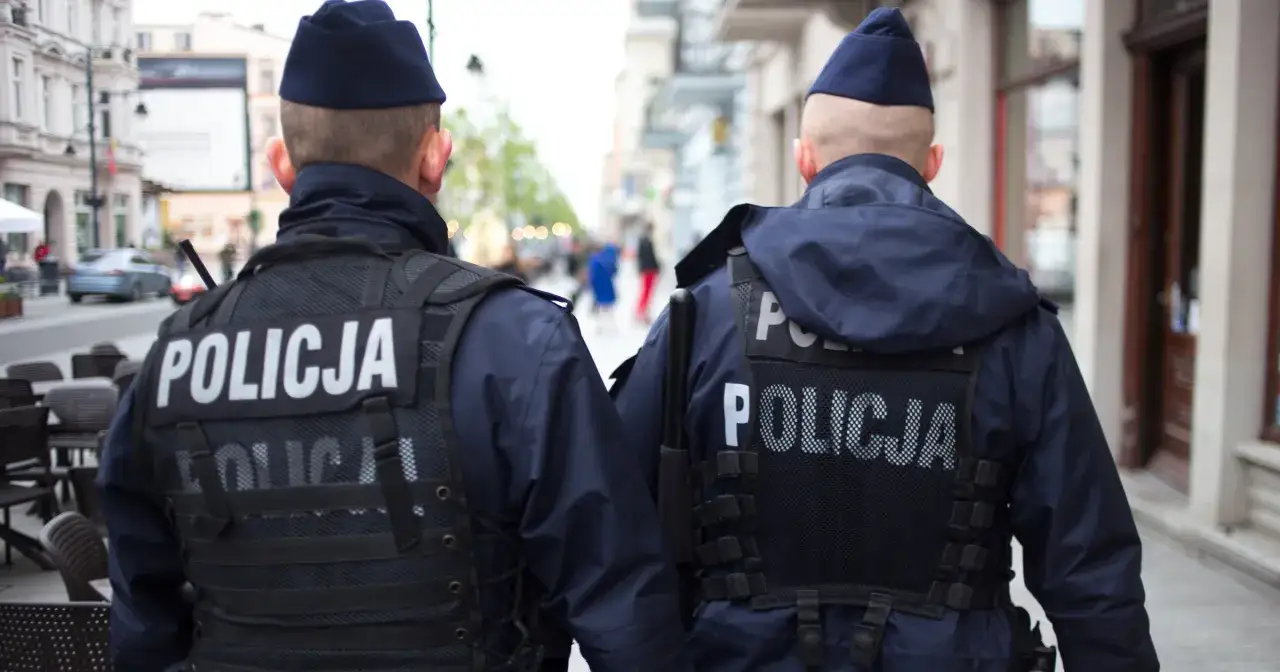 Dwóch policjantów w mundurach patrzy w stronę ulicy, gotowych interweniować w przypadku zakłócania miru domowego.