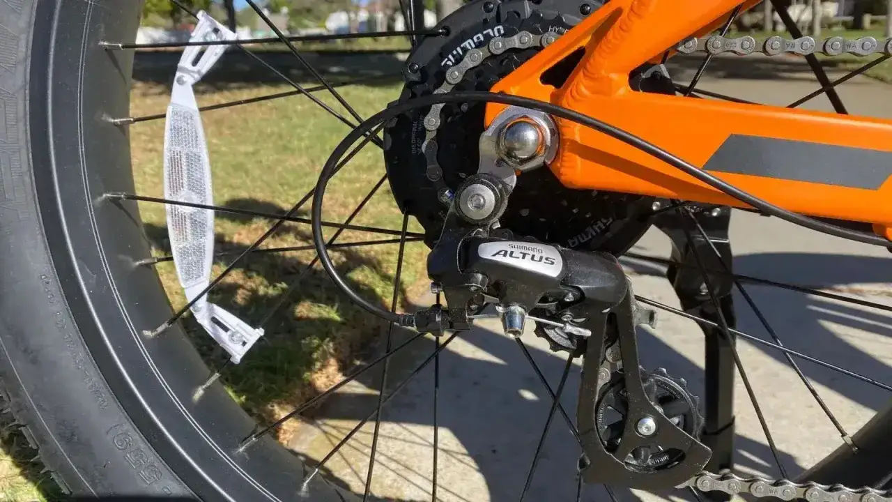 Jak założyć łańcuch na tylną przerzutkę Shimano Altus. Widok na kasetę, przerzutkę i pomarańczową ramę roweru.