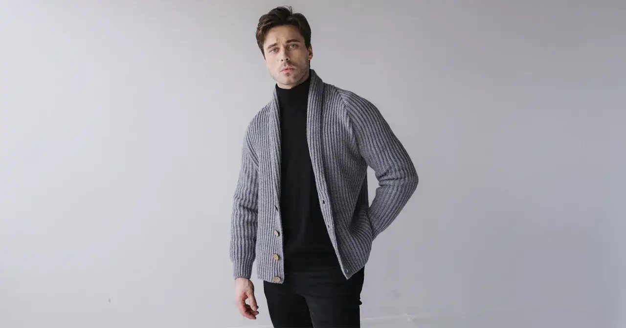 Eleganckie stylizacje na święta bożego narodzenia: mężczyzna w szarym kardiganie i czarnym golfie, gotowy na świąteczne spotkania.