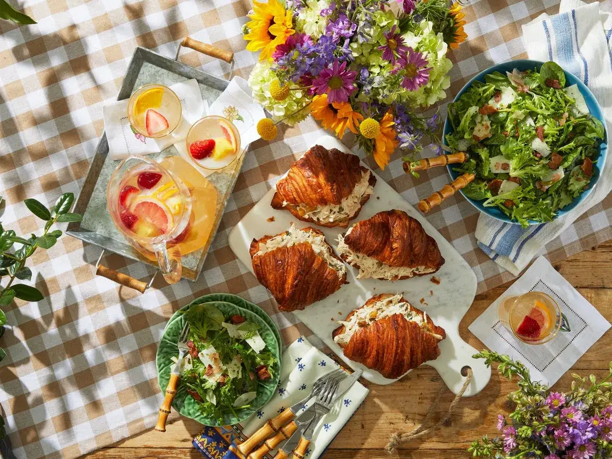 Leckere Croissants mit H&uuml;hnchensalat, frischer Salat und erfrischende Getr&auml;nke &ndash; tolle Picknick-Ideen f&uuml;r einen sonnigen Tag.