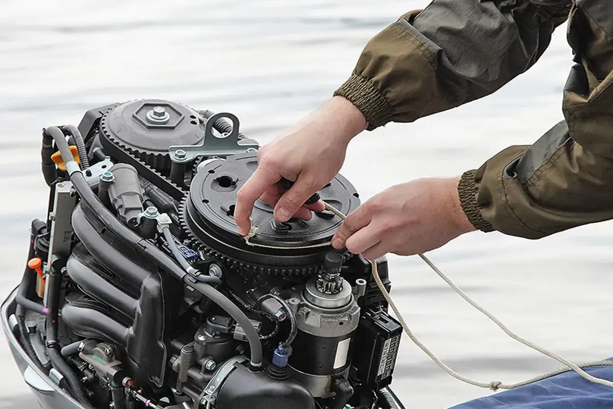 Mains qui tirent sur la corde d'un moteur 4 temps ne d&eacute;marre pas, sur fond d'eau.