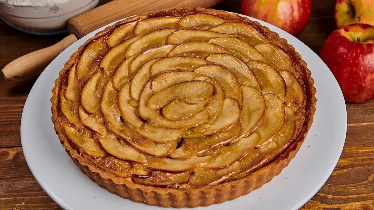 Tarta de manzana dorada, con láminas de fruta dispuestas en espiral sobre una base crujiente. Perfecta para compartir.