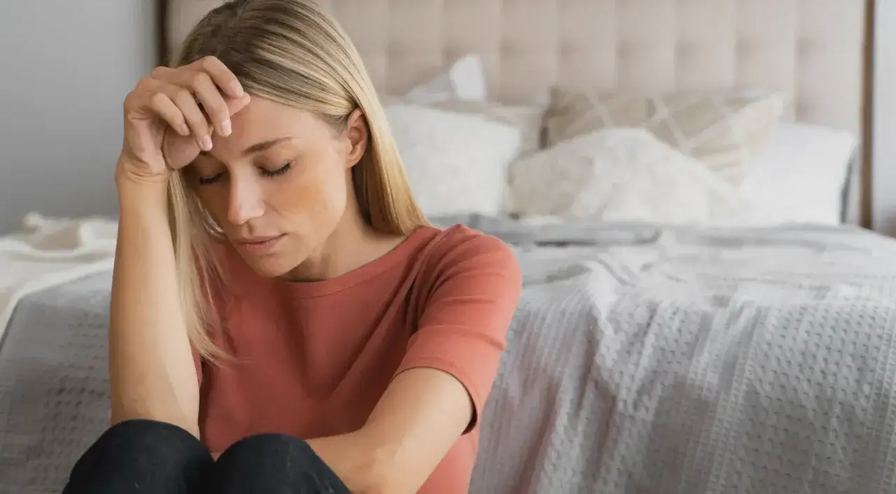 Kvinna med slutna ögon, pannan i handen. Kanske en känsla av depression under klimakteriet, men det finns behandling.