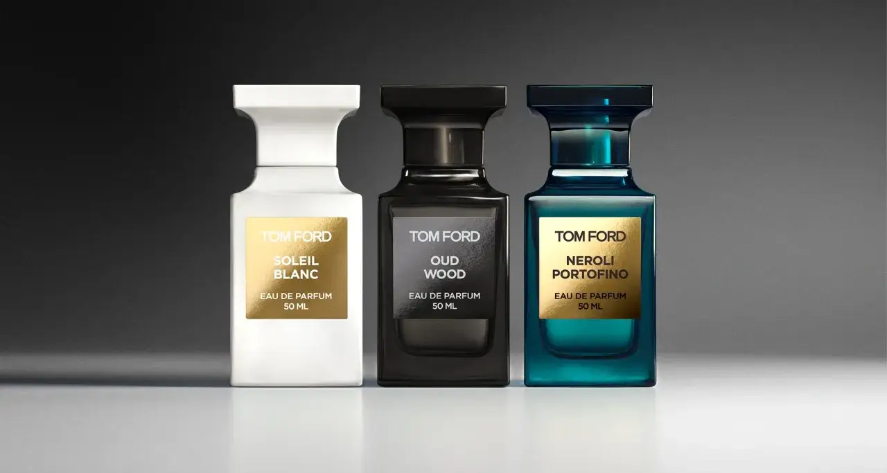 Trzy flakony perfum Tom Ford: biały z napisem Soleil Blanc, czarny z Oud Wood i niebieski z Neroli Portofino.