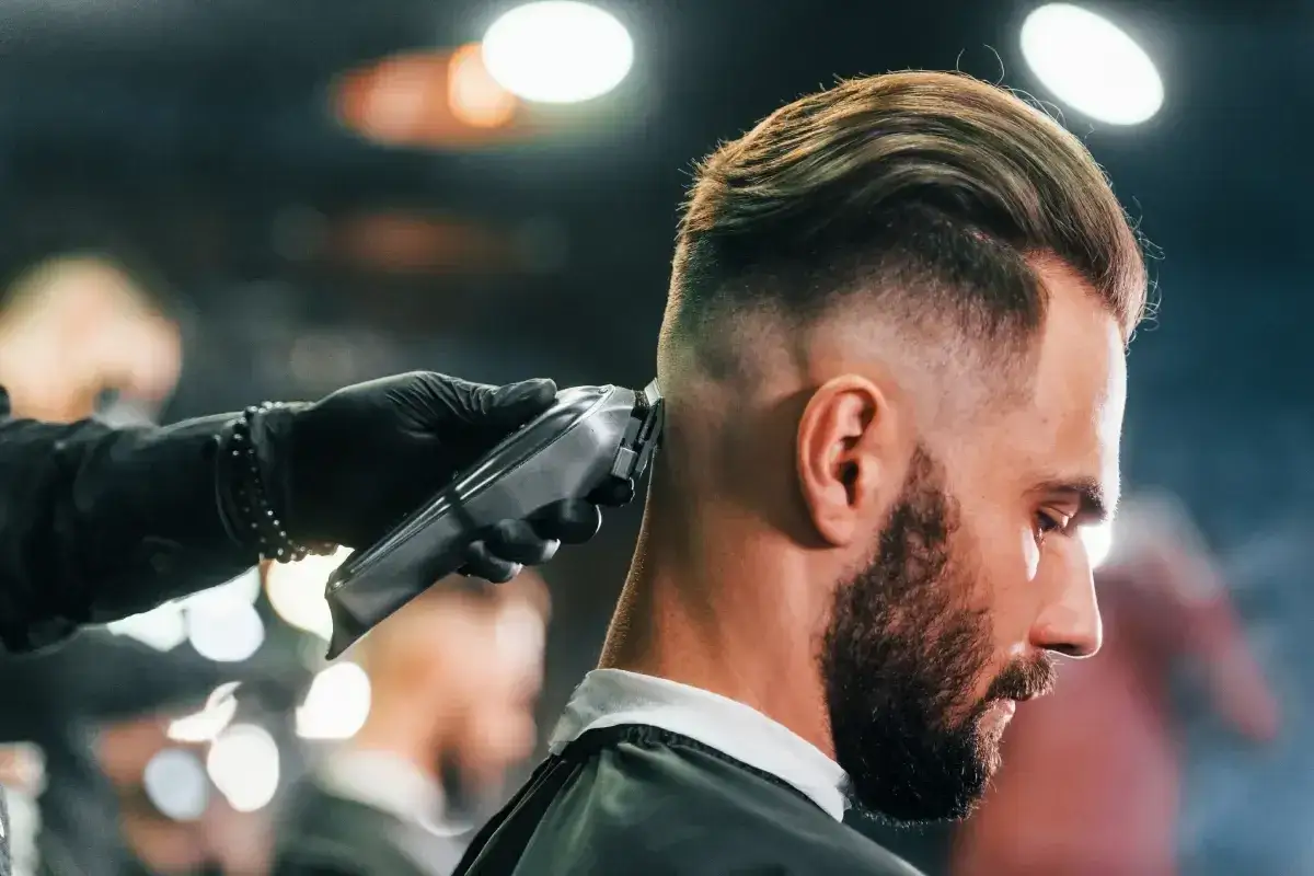 Fryzjer tworzy modny buzz cut, używając maszynki do strzyżenia.