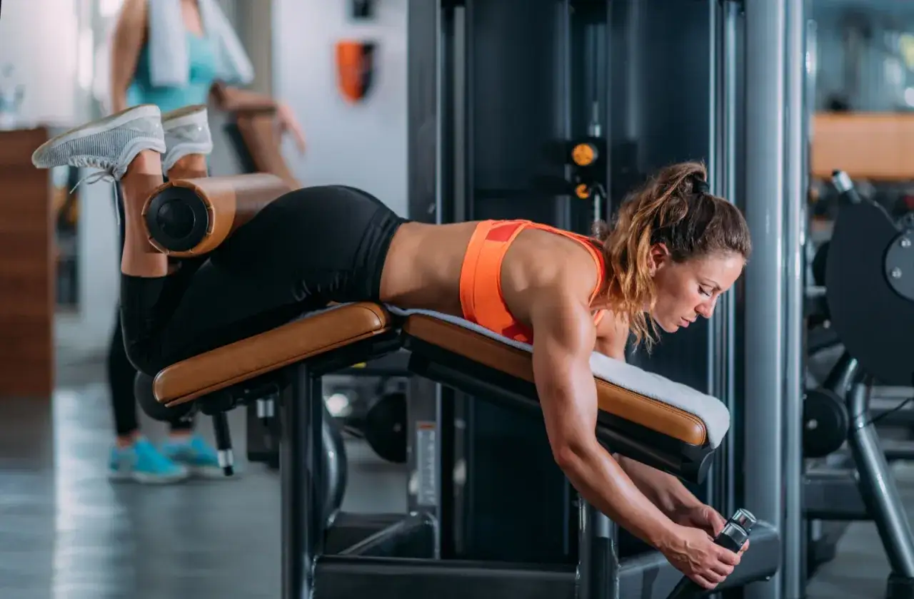 Frau trainiert Beinbeuger auf einem Ger&auml;t im Fitnessstudio.