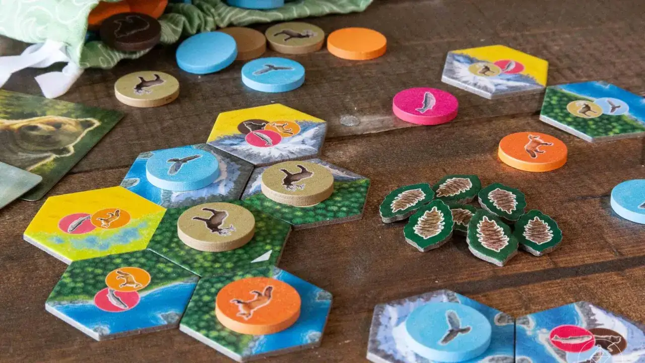 Tasselli esagonali con animali e risorse per **parks gioco da tavolo**. Pezzi rotondi colorati e sacchetto in tessuto.