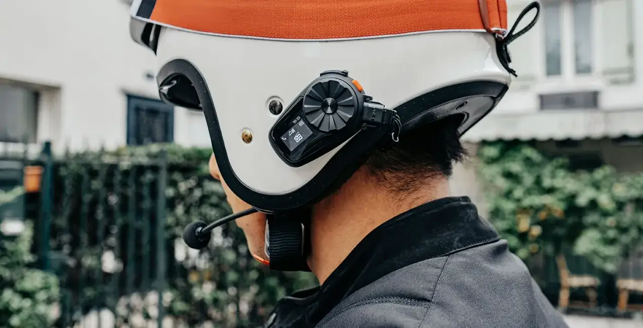 Kask motocyklowy z zamontowanym interkomem Sena 5S. Urządzenie pokazuje ikonę telefonu i muzyki, gotowe do podr&oacute;ży.