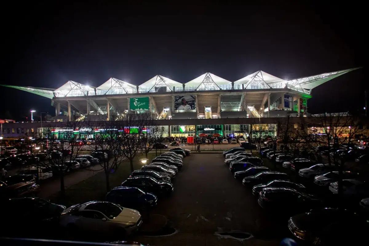 Nocny parking przed stadionem w Warszawie, gdzie tłumy zebrały się na koncert Armin van Buuren.