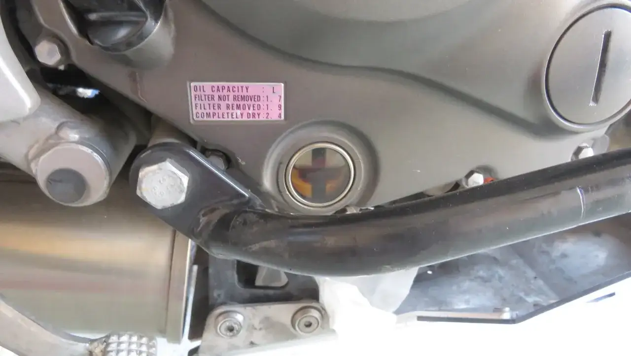 Ventana para comprobar aceite moto. Muestra el nivel de aceite en la moto, con una etiqueta indicando la capacidad.