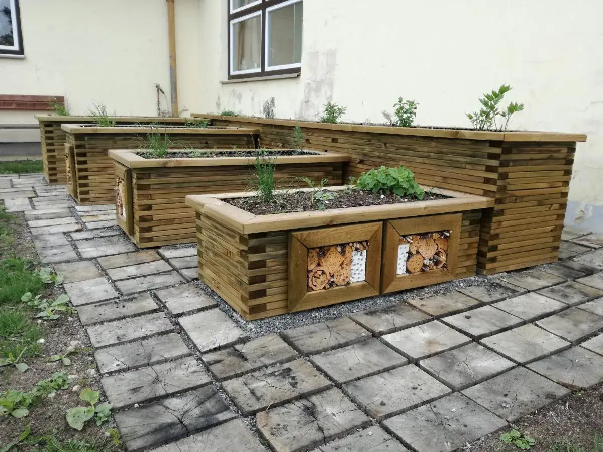 Drewniane podwyższone grządki z ozdobnymi panelami, idealne do ogrodu. Zastanawiasz się, czym impregnować deski na podwyższone grządki? Wybierz naturalne oleje lub impregnaty.