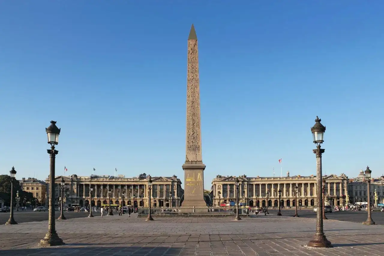 Place de la Concorde i Paris med den egyptiska obelisken i mitten, omgiven av ståtliga byggnader och gatlyktor.