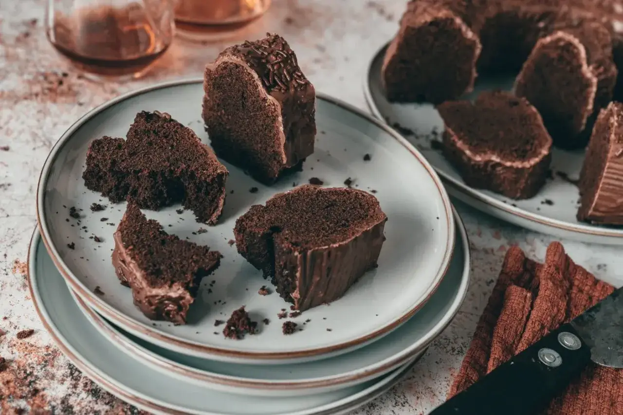Schokoladenkuchenst&uuml;cke auf Tellern, bereit zum Genie&szlig;en. Ein St&uuml;ck ist mit Schokostreuseln verziert. Perfekt zum **rum backen** und genie&szlig;en.
