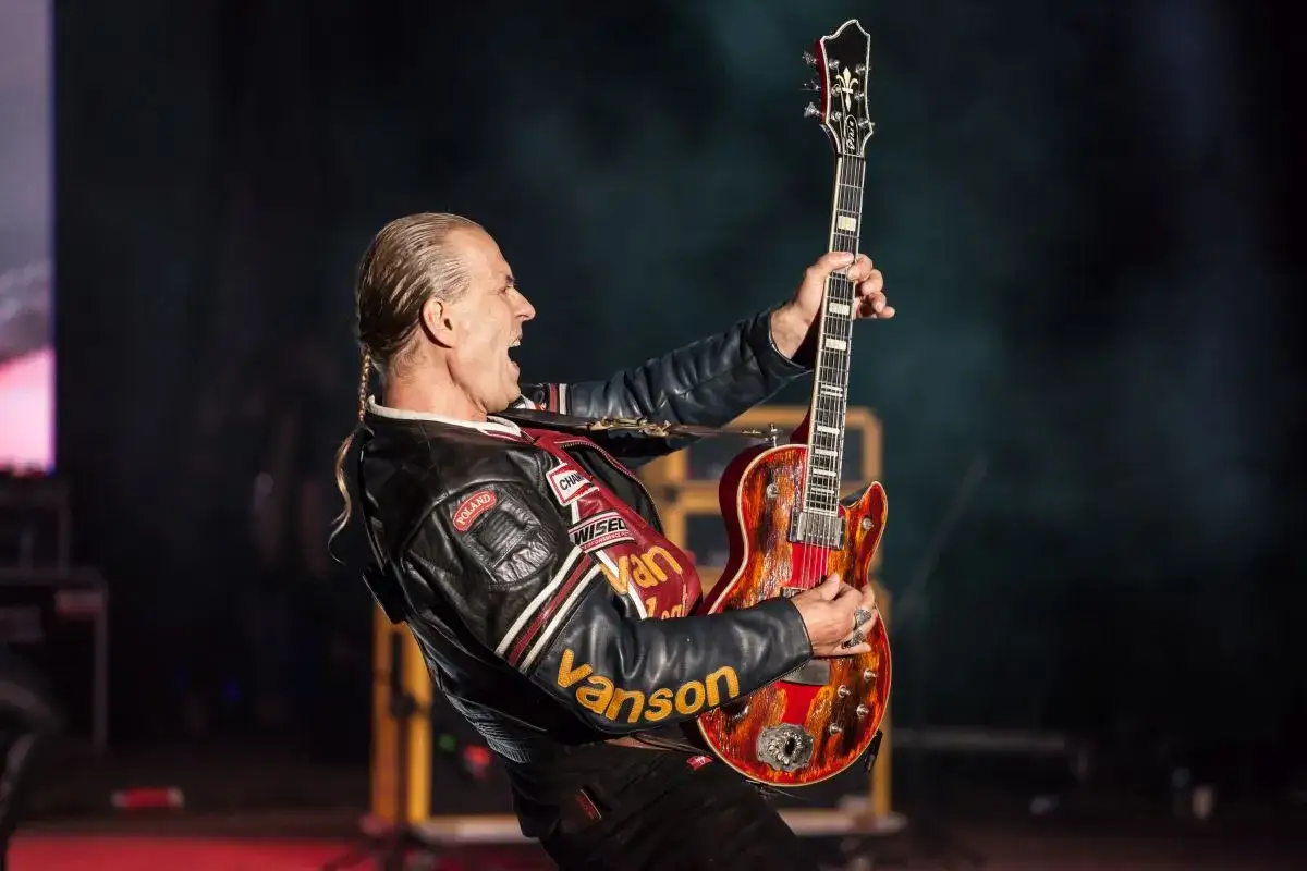 Andrzej Nowak z TSA gra na gitarze, ubrany w skórzaną kurtkę z naszywkami.