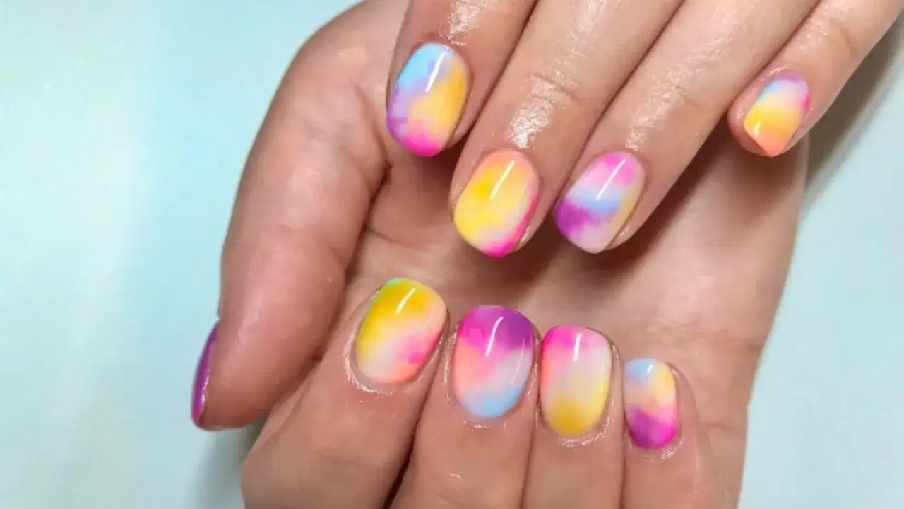 Kolorowe paznokcie na marzec w stylu tie-dye, przypominające tęczę.