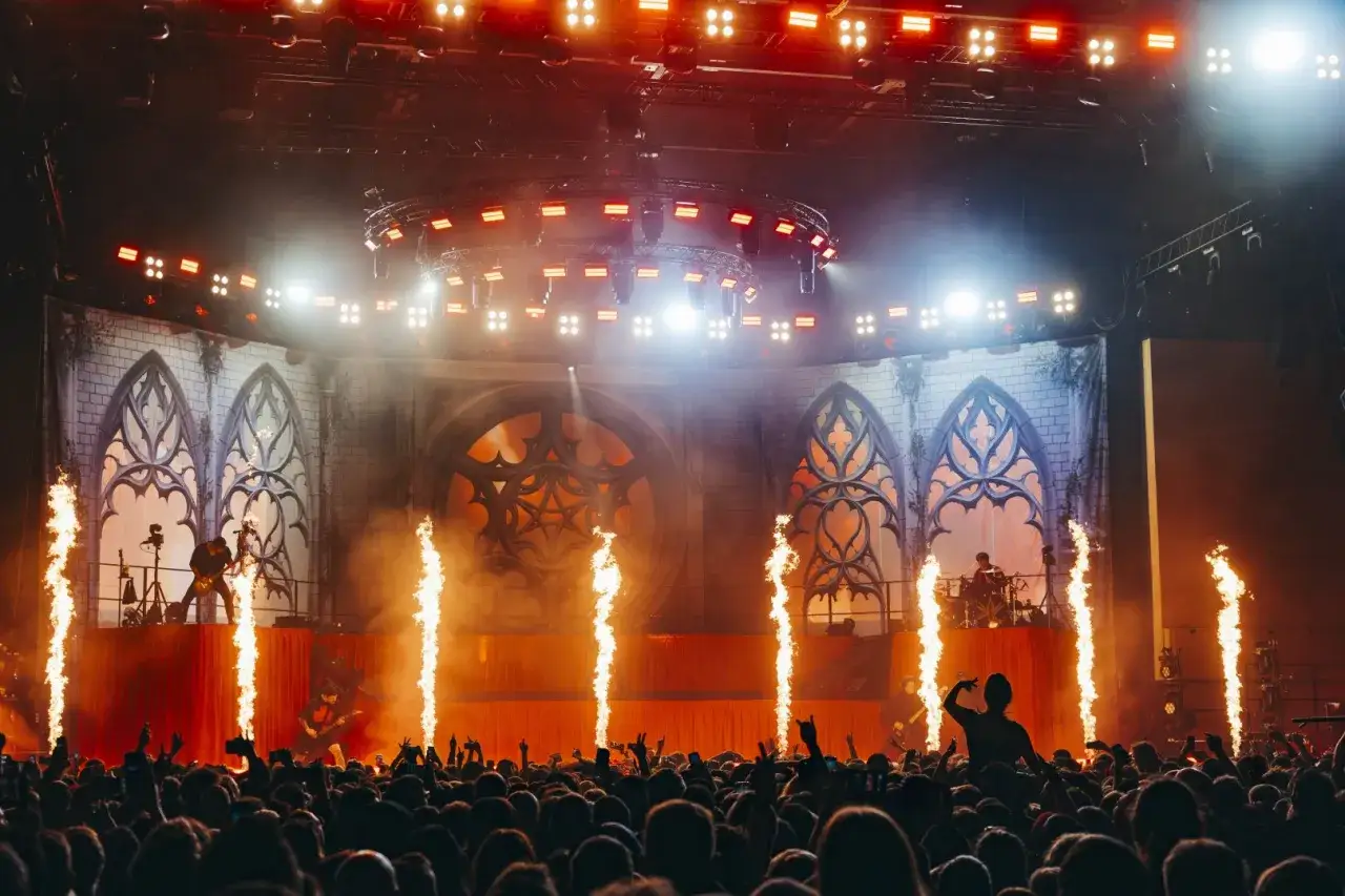 Koncertowy chaos! Członkowie Bring Me The Horizon na scenie, płomienie, światła i tłum szalejący w rytm muzyki.