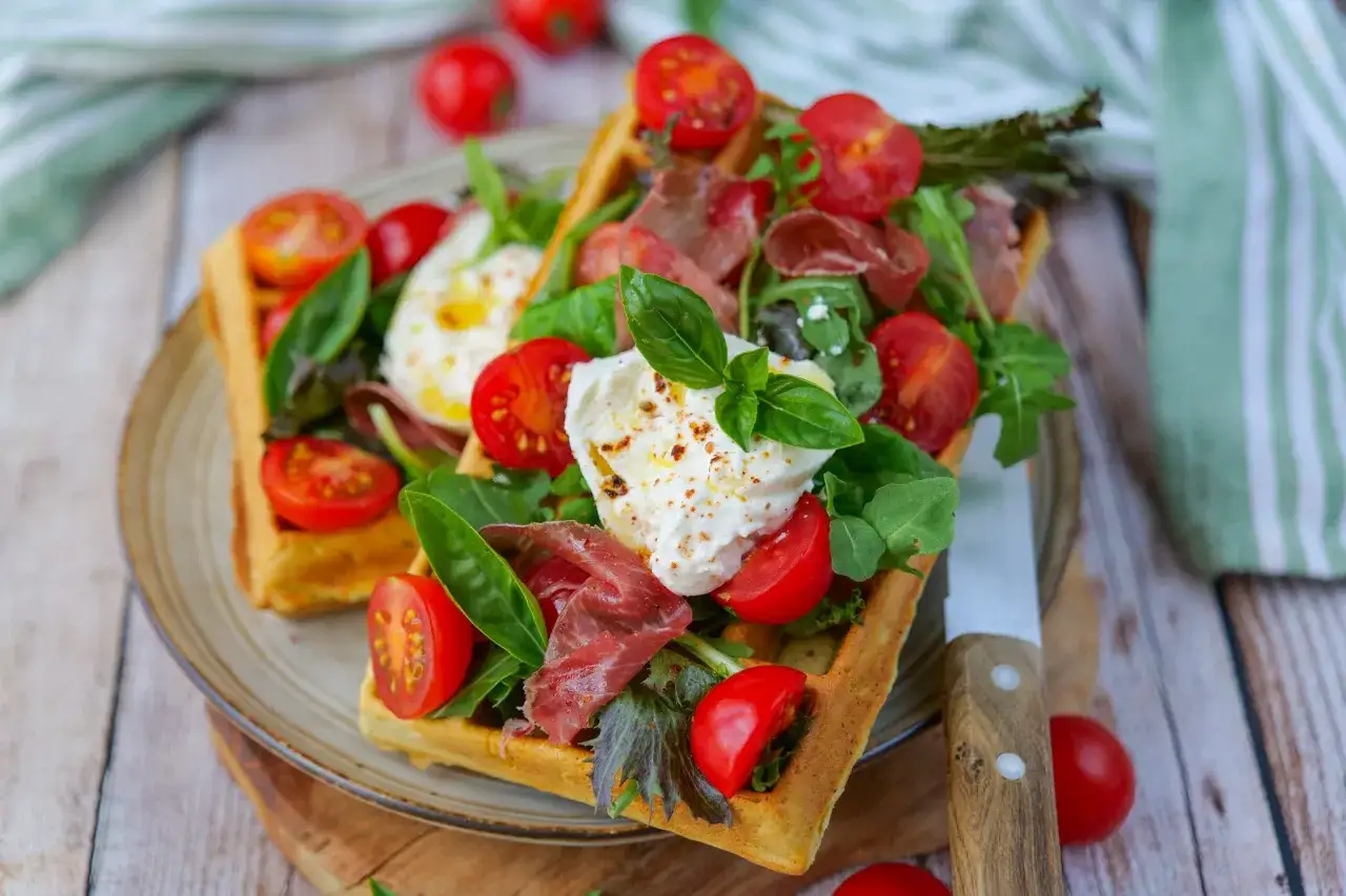 Gaufres sal&eacute;es garnies de burrata cr&eacute;meuse, tomates cerises, roquette et jambon cru. Une recette gourmande et facile &agrave; r&eacute;aliser.